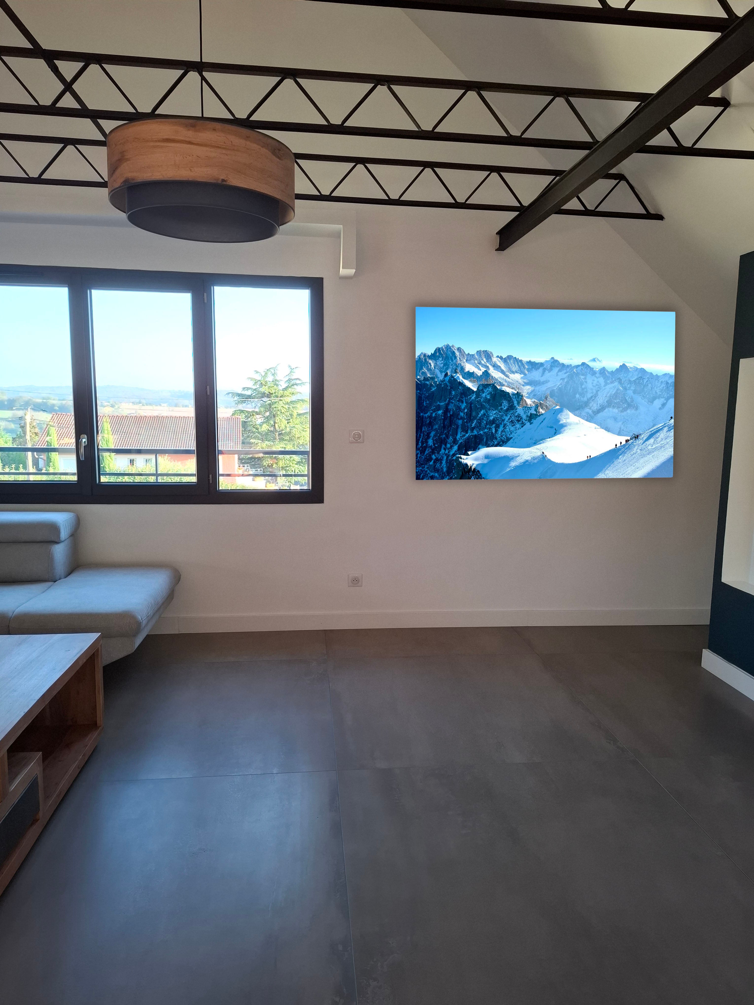 Simulation loft : grand tableau photo de crêtes enneigées — rendu mat anti-reflet au salon, format 70×100