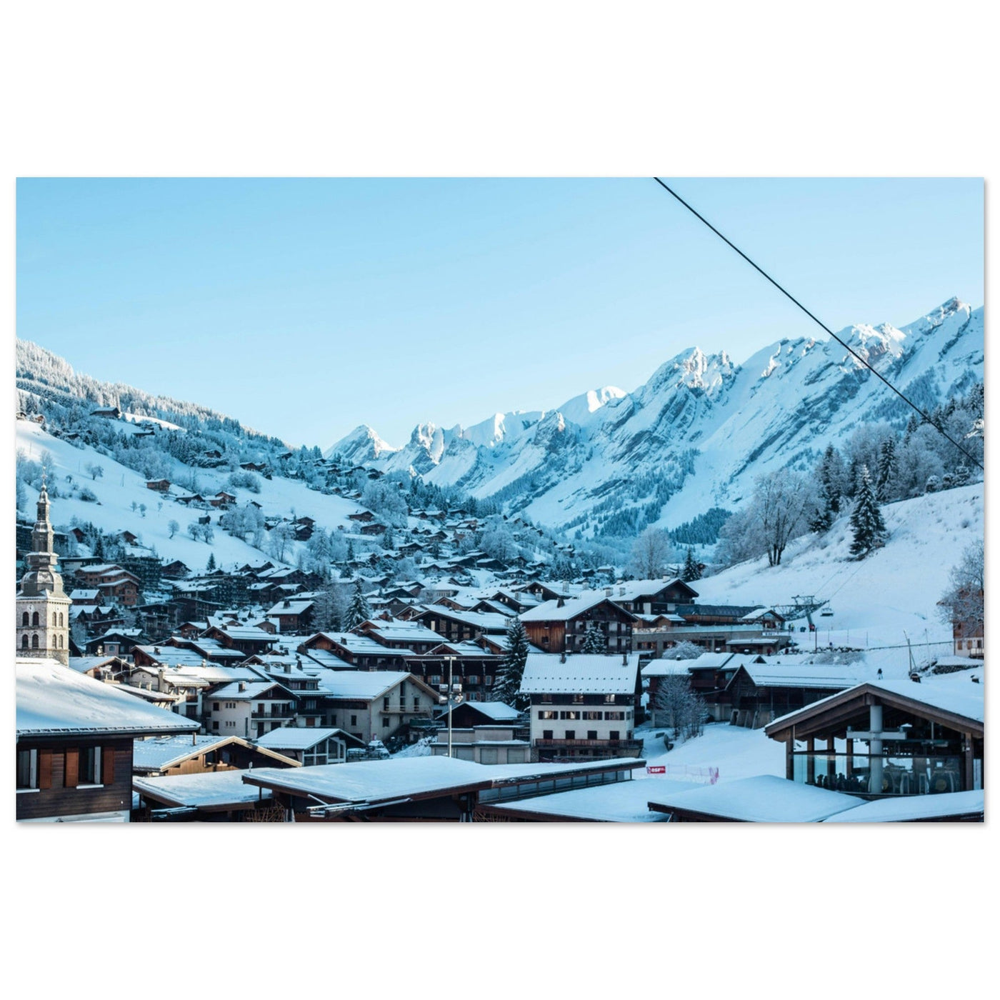 Village de La Clusaz enneigé, son clocher et les crêtes des Aravis en Haute-Savoie