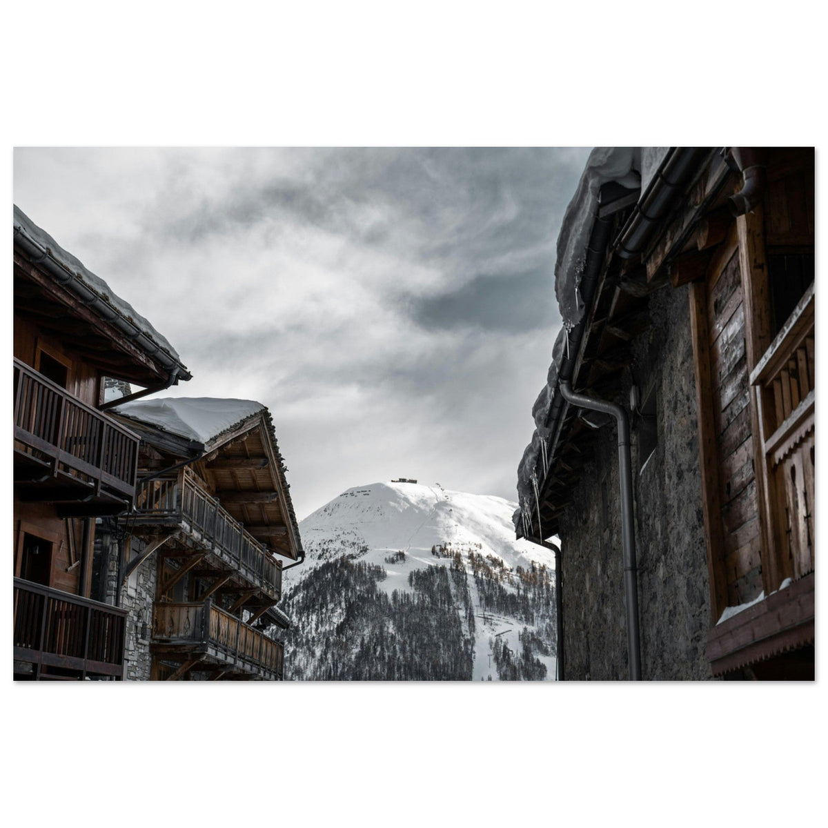 Chalets de pierre et de bois à Val d’Isère sous la neige, face aux pentes de Savoie