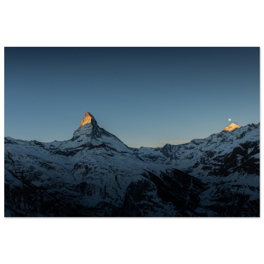 Cervin éclairé par les premières lueurs avec la lune encore visible au-dessus de Zermatt